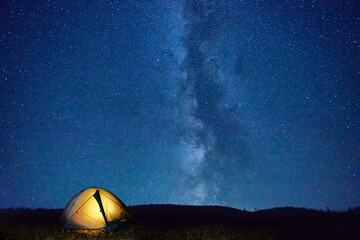 Canvas Print - Illuminated tent in mountains under night dark blue sky with many stars