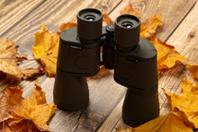 Binoculars For Hunting On A Wooden Background With Yellow Leaves.