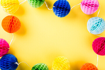 Wall Mural - Festive yellow background with colorful paper balls. Greeting card concept voor birthday, party, invitation, carnival. Copy space, top view, flat lay.
