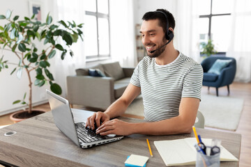 Wall Mural - remote job, technology and people concept - happy smiling man with headset and laptop computer havin