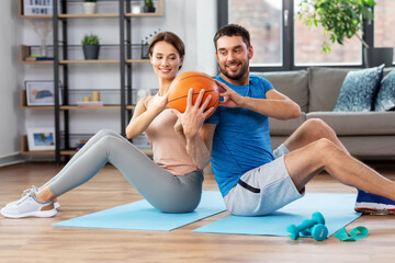 Wall Mural - fitness, sport and healthy lifestyle concept - happy couple exercising with ball at home