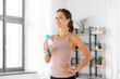 © Syda Productions - sport, fitness and healthy lifestyle concept - smiling young woman with bottle of water at home