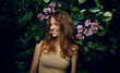 © EkaterinaJurkova - Beautiful young woman with smooth tanned skin laughs cheerfully while standing against the background of exotic plants and flowers. Natural cosmetics, skin care.