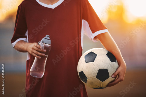 Soccer Boy in Jersey Shirt Holding Water Bottle and Soccer Ball. Sporty Child in Soccer Clothes on a Sunny Morning Training. Junior Football Activity Background