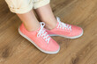 © Pavlo Vakhrushev - Casual pink shoes sneakers on woman feet on wooden floor background