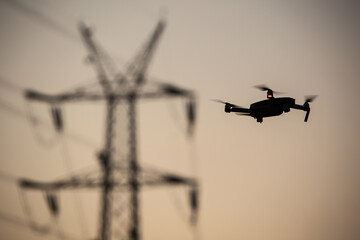 Wall Mural - silhouette of flying drone close to the electrical wire/ drone safety.