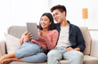© Prostock-studio - Cheerful Asian Couple Using Digital Tablet Browsing Internet At Home