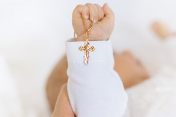 The sacrament of the baptism of a child. The kid is holding a cross. Selective focus.