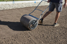 Soil Preparation Before Sowing The Lawn With A Soil Cultivator. Soil Loosening, Raking, Sowing. The Seed Is Repaired By Rolling With A Metal Hand Roller, Which Is Filled With Water, It Will Be Heavier