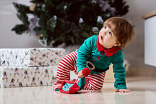 A Little 12-month-old Christmas Elf With A Christmas Tree And Gifts