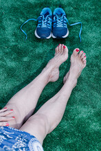 Old Lady With Toenails And Red Hand Painted Sitting On Synthetic Grass