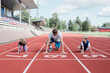 © Cavan Images - Father along with his kids getting ready to run on running track