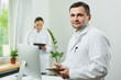 © Roman Tyukin - A kind caucasian doctor with a notebook and a pen records the patient’s medical history in a hospital. A female therapist is doing notes in a clipboard near an all in one computer in a clinic.