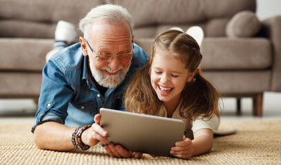 Wall Mural - Grandfather and granddaughter using tablet on floor.