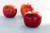 Fototapeta  - Three red apples with focus on the foreground and blur background on a white table. Selective focus