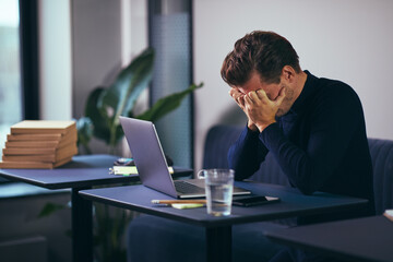 Stressed businessman with his head in his hands at work