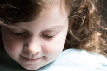 Wall Mural - A young girl at home lit by natural light scared sad during self isolation at home during COVID-19 blue eyes anxious curly brown hair