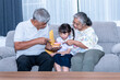© Anatta_Tan - Portrait images of Asian family, Grandpa and elderly grandmother, persuading granddaughter to eat a snack, is sweet donut, to people and pampering concept.