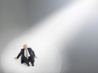Businessman sitting and looking up at source of spotlight
