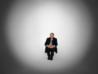 Middle aged businessman sitting in spotlight