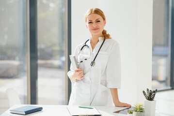 Portrait of young woman doctor with white coat standing in hospital