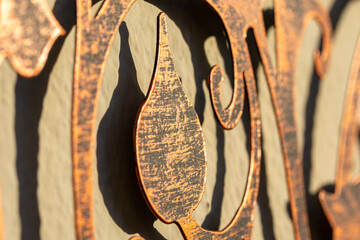 Detail of a coppery metal ornament and its shadow on a wall