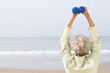 Rear view of a African American senior woman exercising with dumbbells at beach