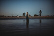 © Cavan Images - Beautiful woman in long dress standing on the beach at sunset