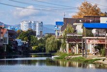 The Bank Of The Dagomys River Is Built Up With Small Cottages With Garages For Boats, High-rise Buildings And Mountains On The Horizon In Sochy, Russia