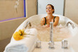 Happy woman enjoying in bathtub during hydrotherapy at health spa.
