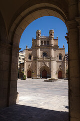 Wall Mural - Main square of Castellon de la Plana through an arch with the Co-Cathedral of Santa Maria in the background on a sunny day with a blue sky, Spain