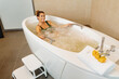 Happy woman relaxing in spa's bathtub during hydromassage treatment.