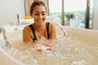 © Drazen - Happy woman using bath salt during hydrotherapy at health spa.