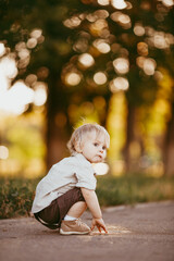 Wall Mural - A small blond boy dressed in a vintage jumpsuit in a field at sunset