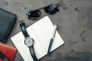 Businessman's accessories including notepad, watch and purse on dark grey background