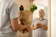 © Drazen - Happy senior man receiving groceries delivery at home.