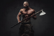 Furious And Bearded Viking Warrior With Naked Torso And Huge Biceps Prepared To Fight Holding His Weapon In Dark Background.
