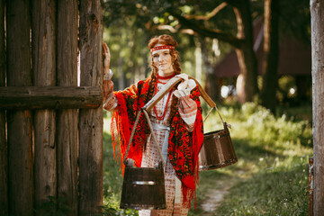 Beautiful Slavic girl with long blonde hair and brown eyes in a white and red embroidered suit and a yoke on her shoulders.Traditional clothing of the Ukrainian region.