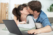 © auremar - happy young couple kissing next to laptop