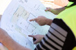© Amelia Soegijono/Austockphoto - Workers' hands pointing to building plans at a construction site