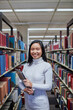 © Jonah Ritchie/Austockphoto - Young Asian student standing in aisle at university library