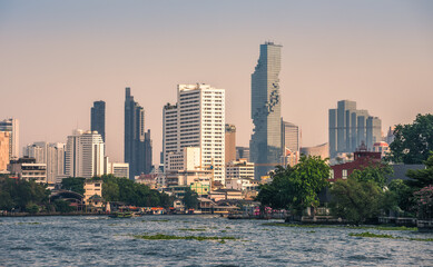 Wall Mural - City Skyline as Seen from the Tourist Boat on Chao Phraya River at Sunset in Bangkok, Thailand