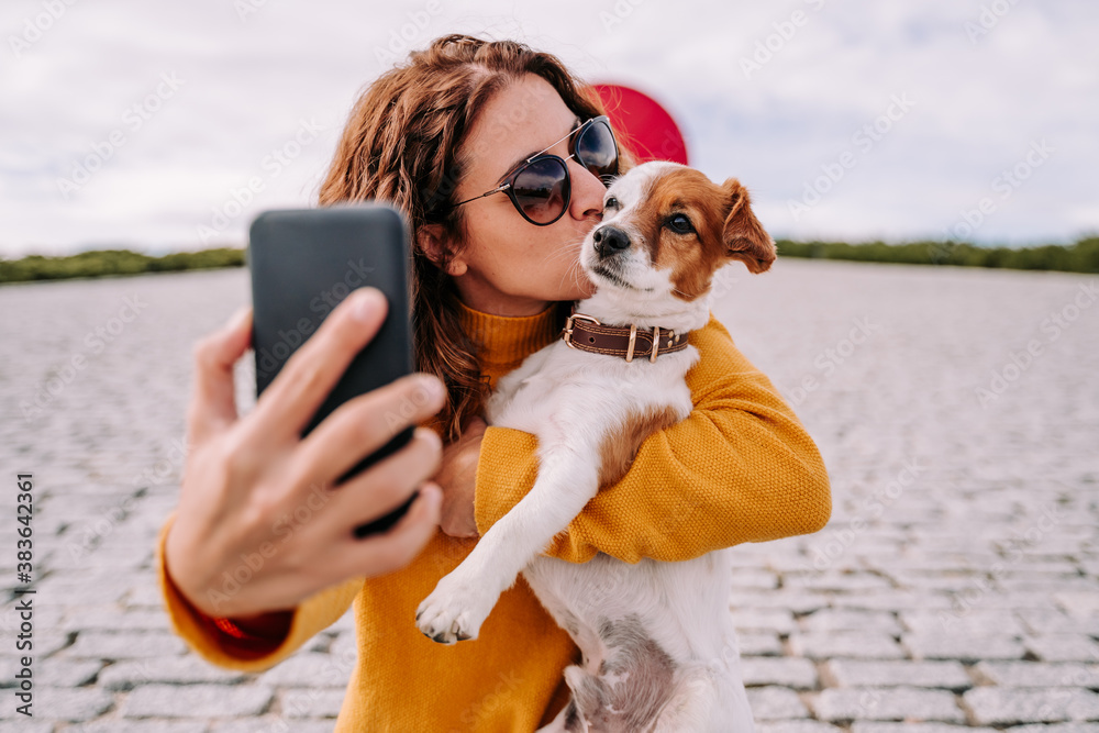 A beautiful woman staying in a park with her cute little dog. She is ...