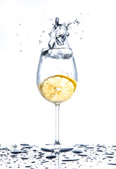 Poster - Lemon splashing into glass of water on white background