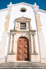 Wall Mural - Entrance to the church. Large wooden door. beautiful landscape of a large and tall church built of white stone. church in portugal. church with a tower with bells