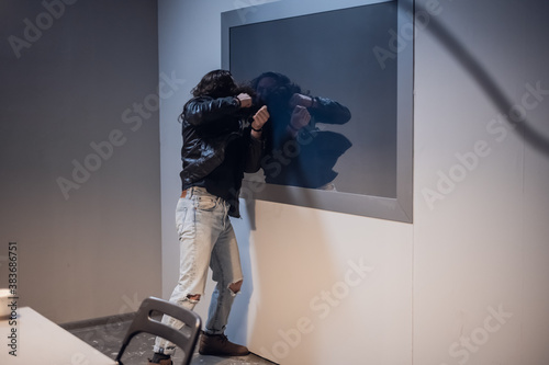 Cuadros en Lienzo A white man with tattoos on his face tries to break the Gesell mirror in the pol