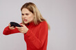 © SHOTPRIME STUDIO - Woman with gamepad in hands playing games emotions lifestyle leisure red shirt light background