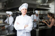 © JackF - Portrait of young confident woman chef in kitchen of restaurant with working staff