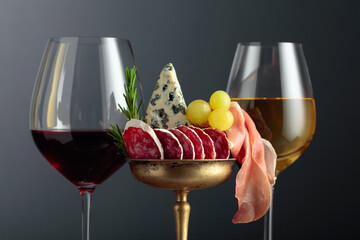 Wall Mural - Wine, blue cheese, dry-cured sausage, grapes, and rosemary on a black background.