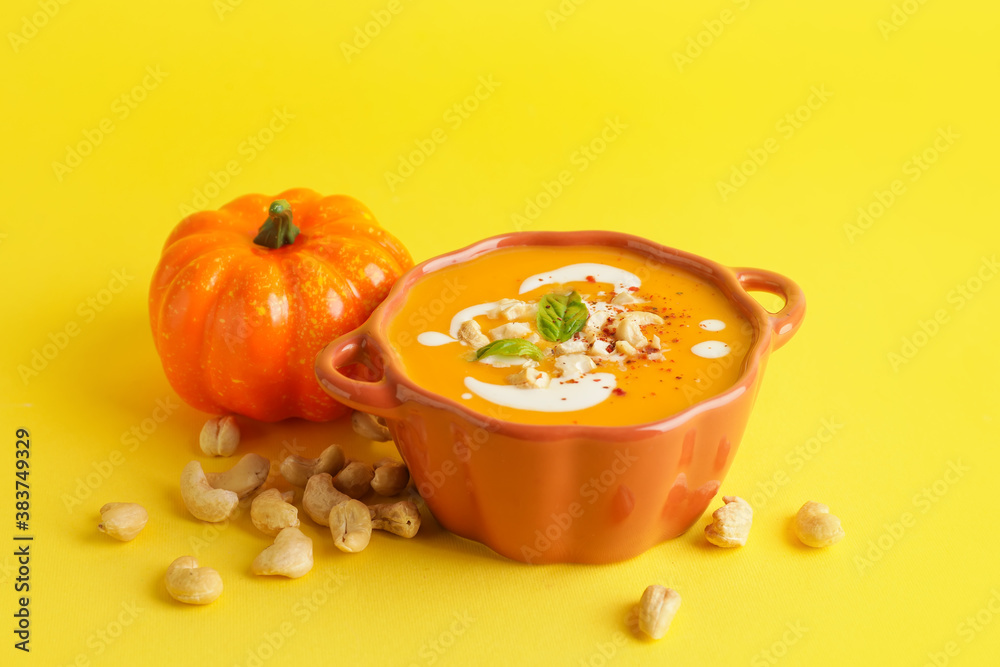 Tasty pumpkin cream soup in pot on color background